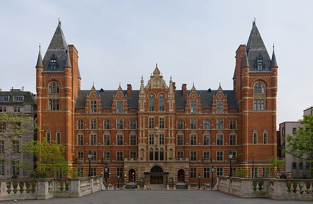 an old brick building with two towers on each side and a walkway leading to it