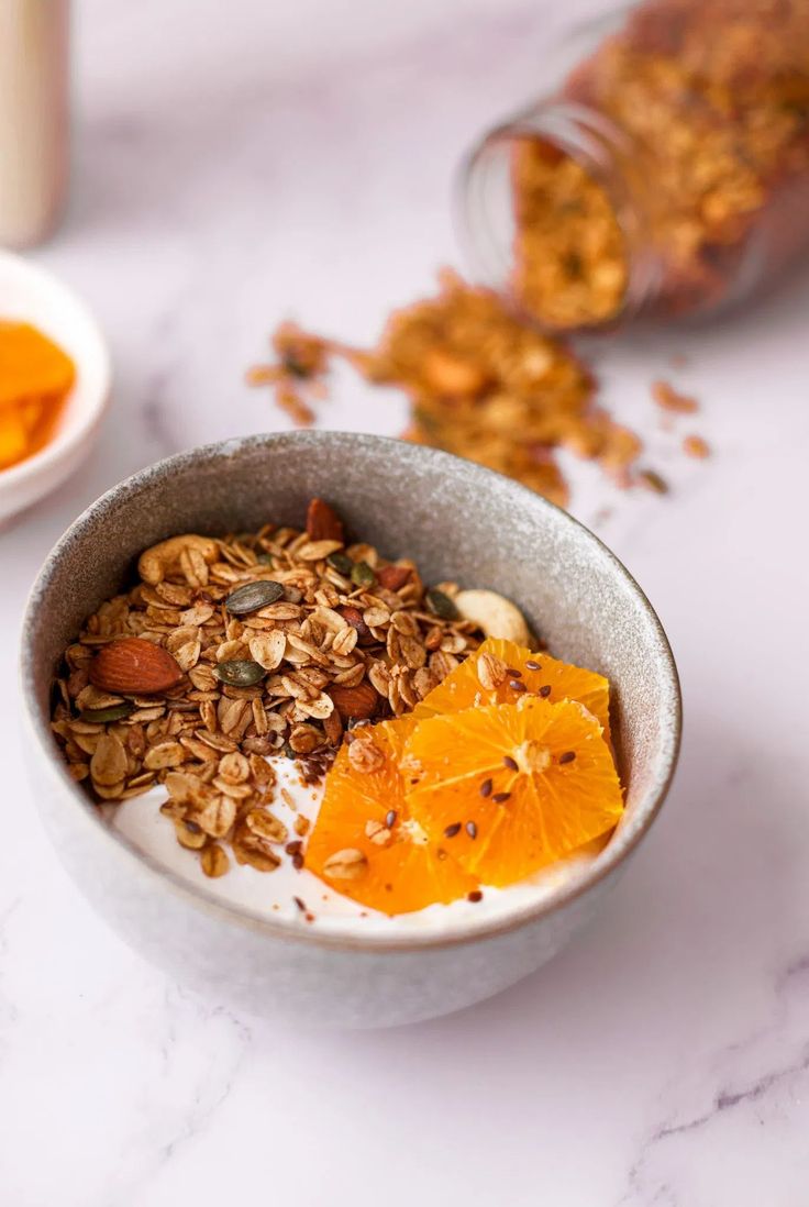 a bowl filled with granola and orange slices