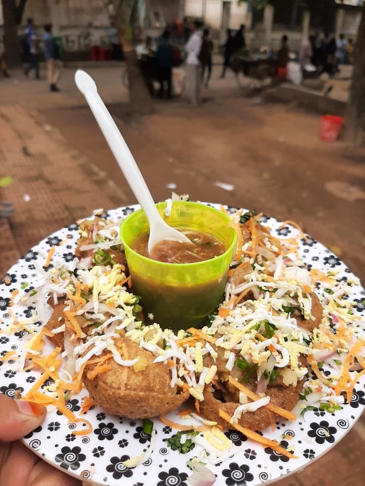 a person holding a plate with food on it and a spoon in the middle of it