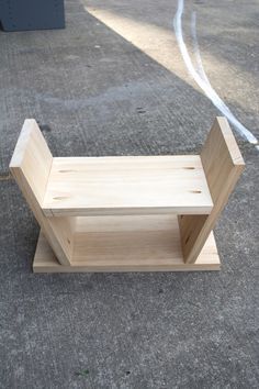 a wooden chair sitting on top of a cement floor next to a metal object with a long handle