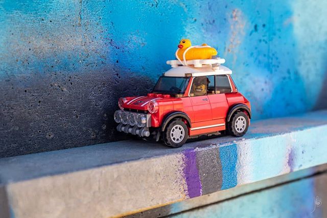 a toy car with a surfboard on top is parked in front of a painted wall