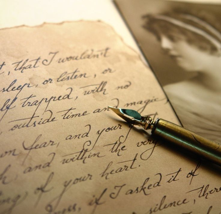 a pen sitting on top of an old letter next to a photo with writing in it