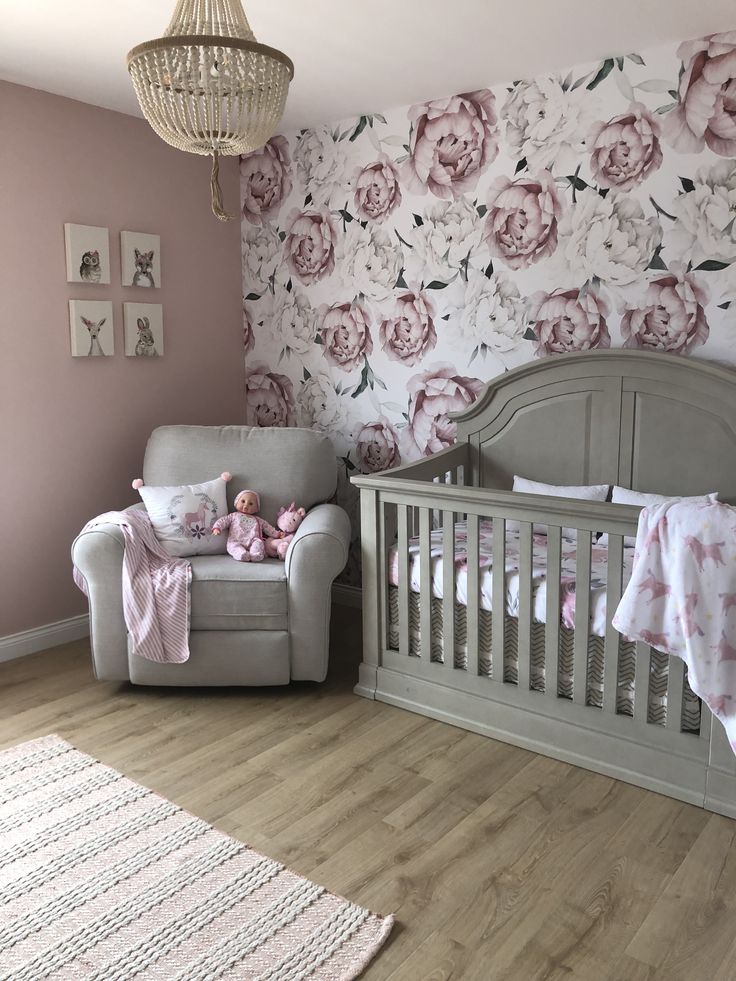 a baby's room decorated in pink and grey with floral wallpaper, crib, rocking chair, and teddy bear