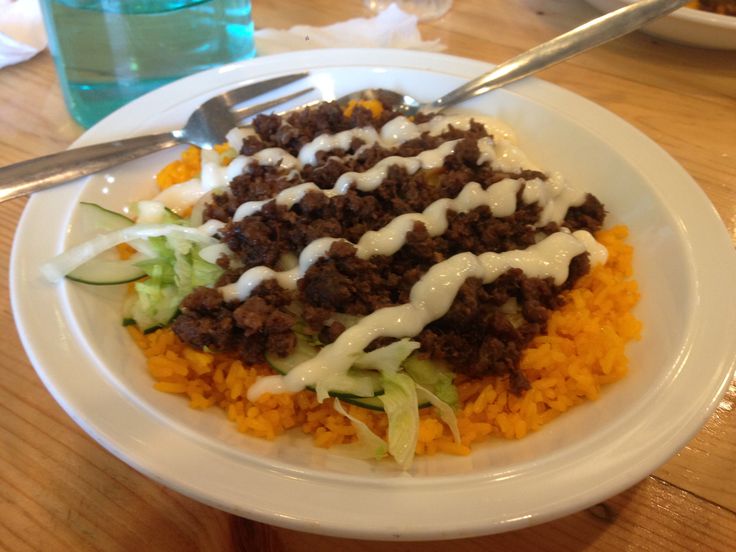 a white plate topped with lots of food on top of a wooden table next to a fork