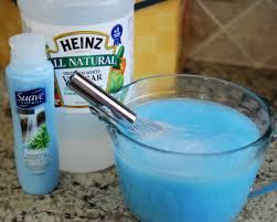 blue liquid in a bowl with a whisk next to it on a counter