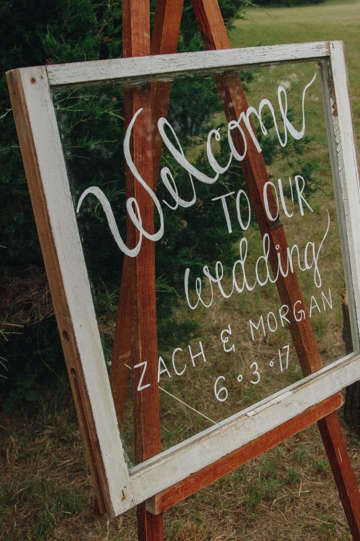 a wooden easel holding a sign that says welcome to our wedding