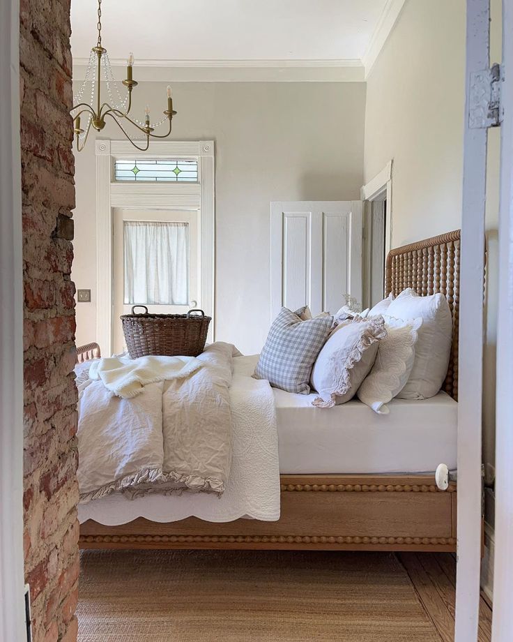 a bed with white linens and pillows in a bedroom next to a brick wall