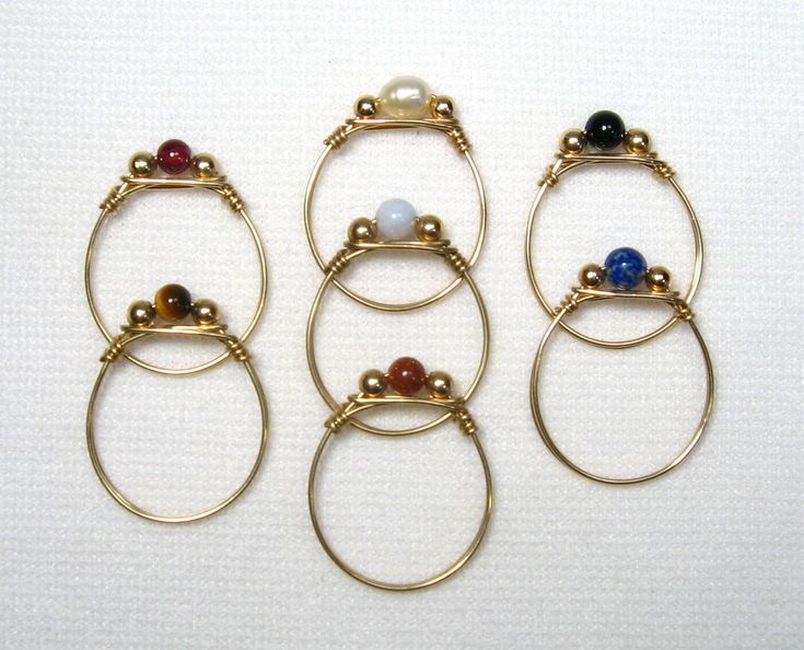 These rings are Gold Filled. They are size 8.5, tied wire rings, made from one piece of gold filled wire which passes through the stone and 3 mm gold filled bead accents. The stone choices are 4 mm rounds, 5-6 mm long oval or cylinder or freshwater pearl. ( sizes are approximate) Handmade by us.     Want a different size, stone or one in Sterling Silver? Contact us.     Lyn's Jewelry, in business operating out of Sunny Syracuse since 1989. Adjustable Stackable Rings With Stones, Wire Wrapped Jewelry Tutorials, Gold Gemstone Ring, Rings Gold, Wire Rings, Beads And Wire, Beaded Rings, Jewelry Tutorials, Wire Wrapped Jewelry