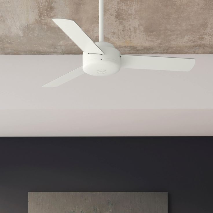 a white ceiling fan mounted on the side of a wall next to a large painting