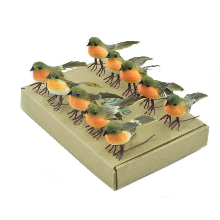 small birds are perched on top of each other in a cardboard box with oranges and green leaves