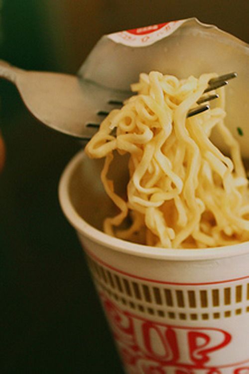 a person holding a fork and bowl of noodles