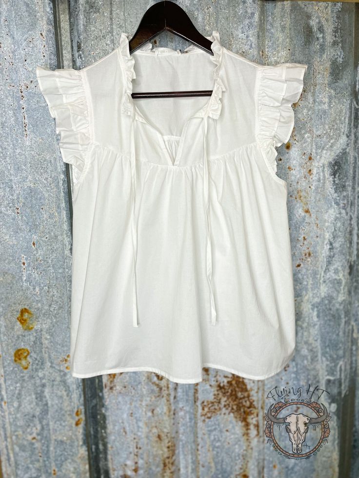 Add a touch of feminine flair to your wardrobe with our White Ruffle V Neck Top. Featuring a flowy silhouette and delicate v neck tie accent, this top is perfect for any occasion. Elevate your style and feel effortlessly chic in this must-have piece! Feminine Flowy V-neck Top, Feminine Cotton V-neck Blouse, Chic Flowy V-neck Peasant Top, Spring V-neck Peasant Top With Ruffles, Flowy Cotton V-neck Blouse, Flowy V-neck Top With Ruffles, Chic Ruffled Peasant Top For Daywear, Chic Flowy V-neck Blouse, Feminine Flutter Sleeve Tops For Daywear