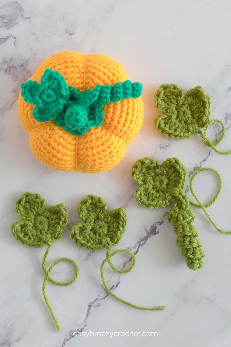 crocheted pumpkins and leaves on a marble surface