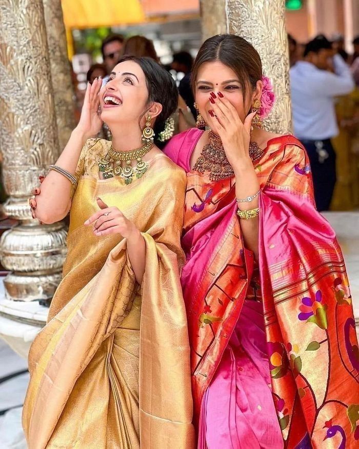 two women dressed in sari are posing for the camera with their hands on their faces