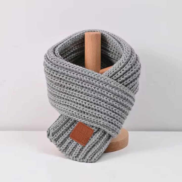 a gray knitted scarf on a wooden stand