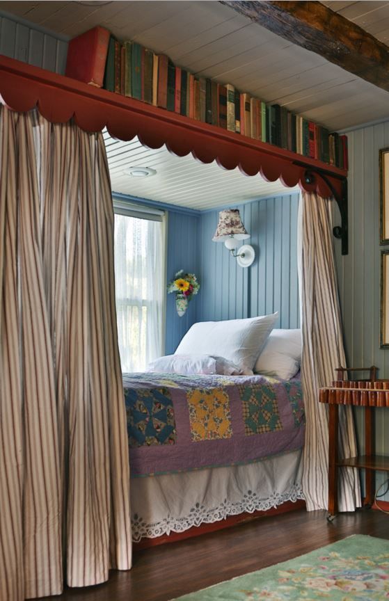 a bedroom with blue walls and striped curtains on the window sill above the bed