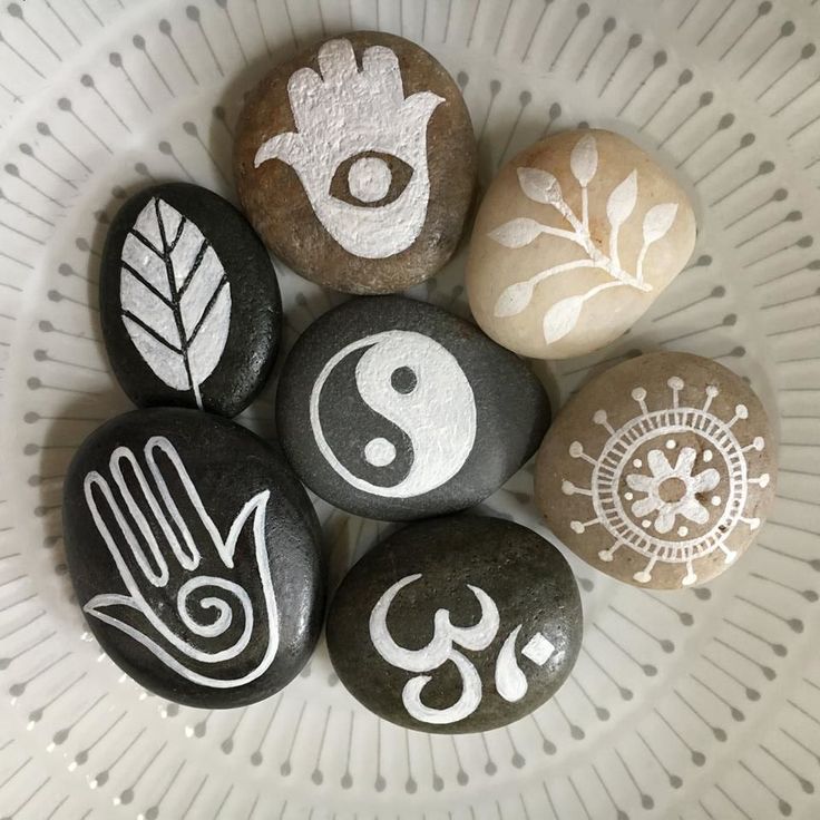 five rocks with symbols painted on them in a circle, sitting on a white plate