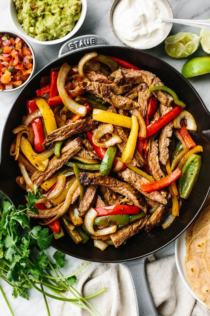 steak fajita in a skillet with peppers, onions and cilantro