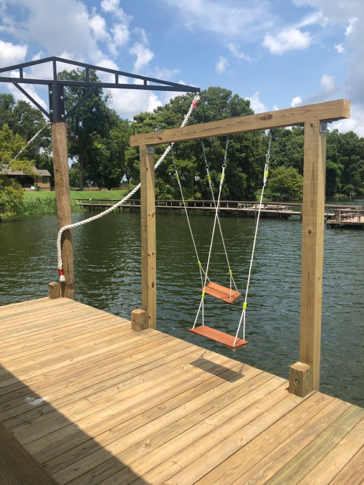 a wooden dock with swings and ropes on it