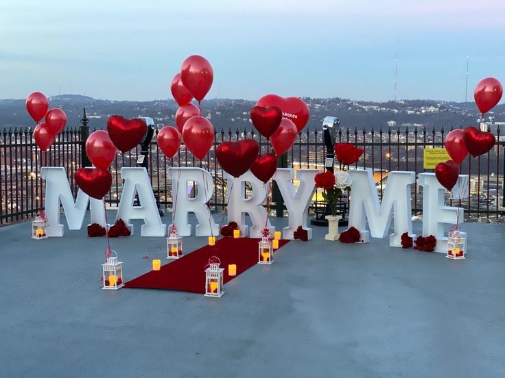 many balloons and candles are placed on the ground in front of a sign that says marry