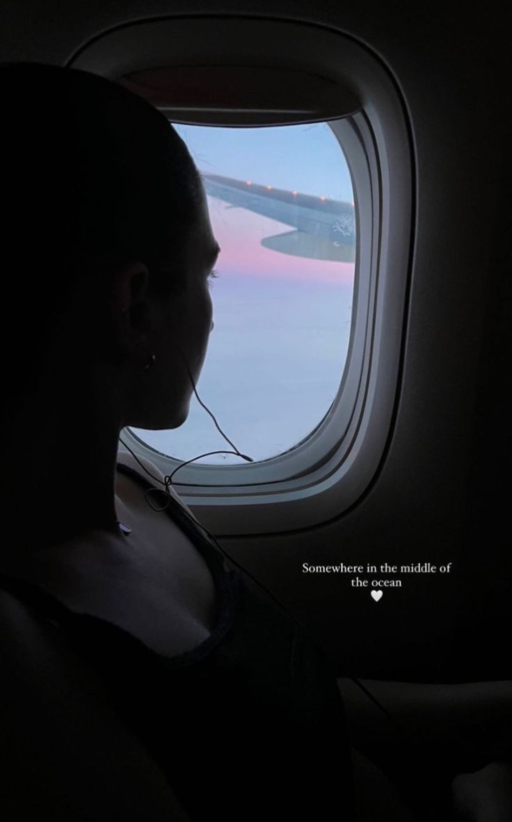 a woman looking out an airplane window at the sky