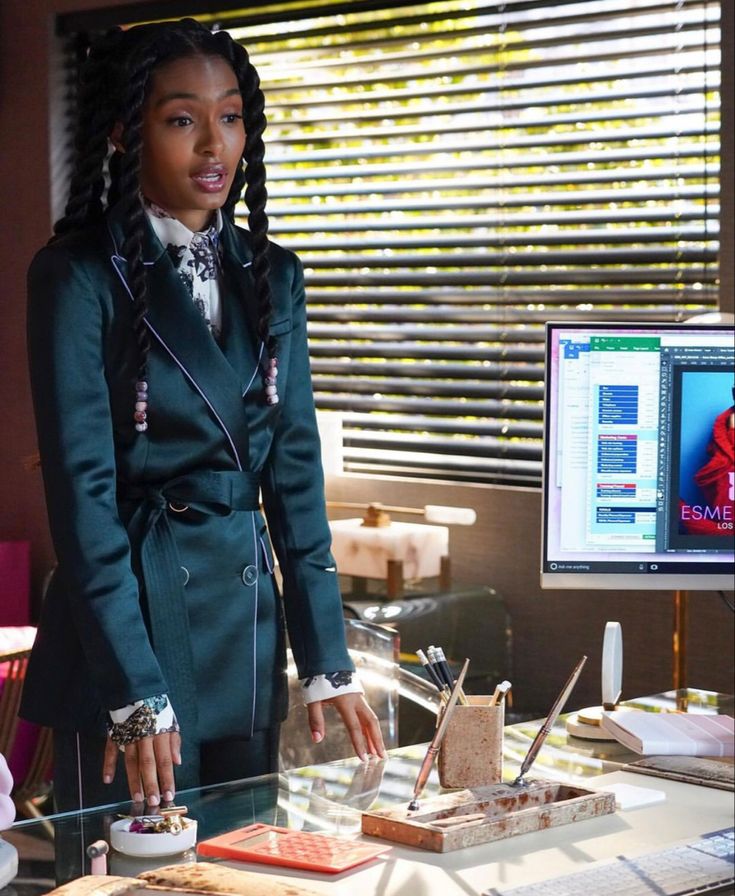 a woman standing in front of a desk with a computer monitor and keyboard on it