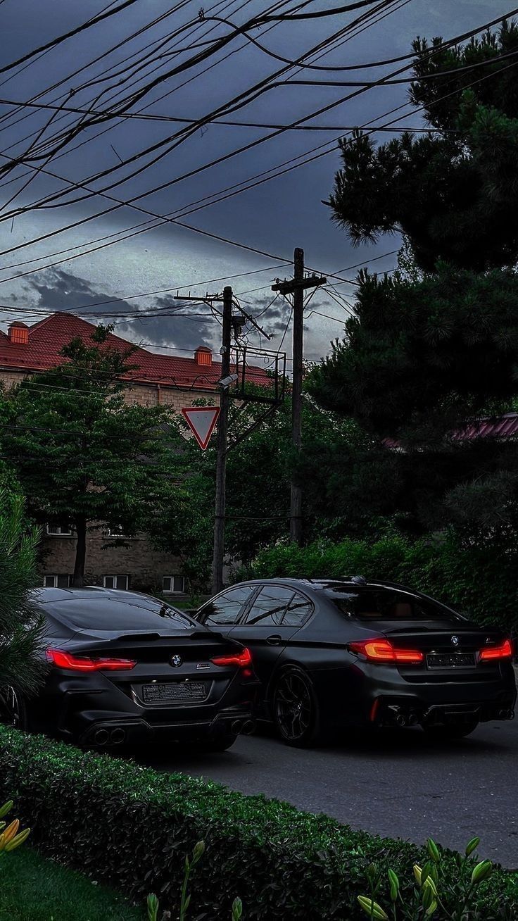 two cars parked next to each other on a street with power lines in the background