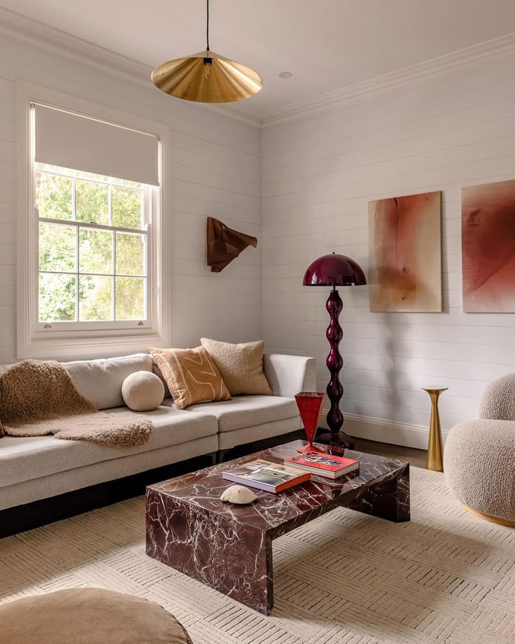 a living room with couches, lamps and pictures on the wall above them in front of a window