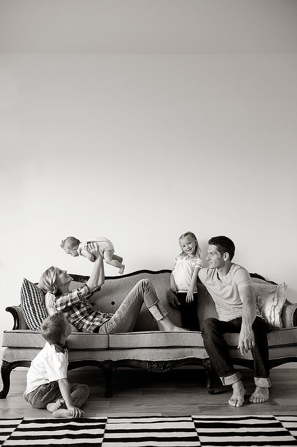 a group of people sitting on top of a couch in a living room next to each other