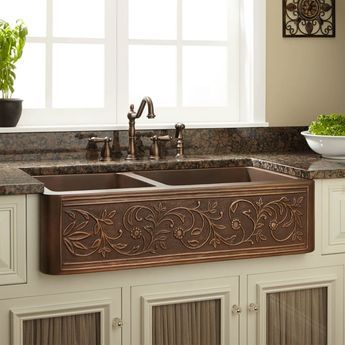 a kitchen sink with an intricate design on the front and side, along with two faucets