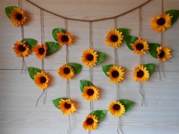 the sunflowers are hanging on the wall with green leafy stems and leaves