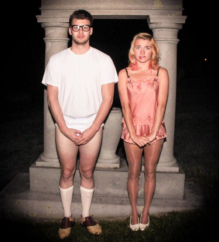 two people standing next to each other in front of a stone structure at night time