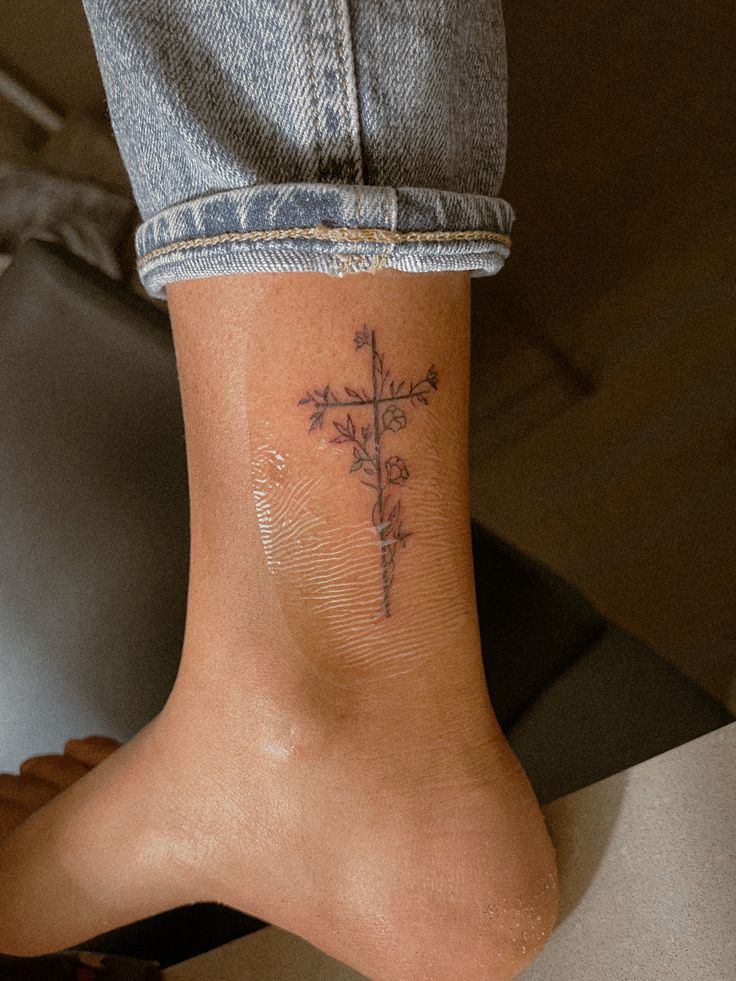 a person with a cross tattoo on their foot