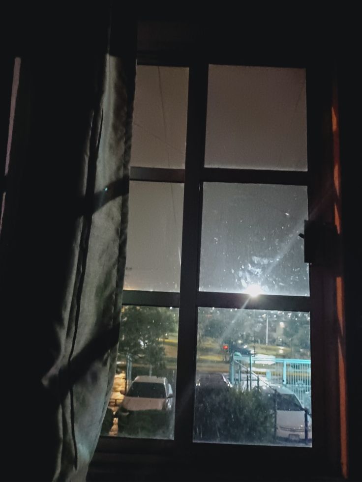 an open window in a dark room with cars outside