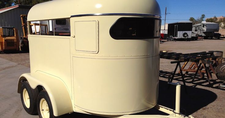 an old white truck parked in a parking lot next to other trucks and trailers,