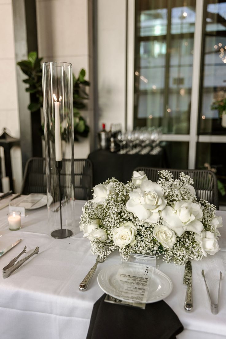 a table with white flowers and silverware on it