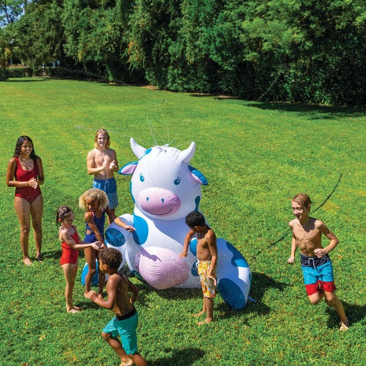 children playing with an inflatable cow on the grass