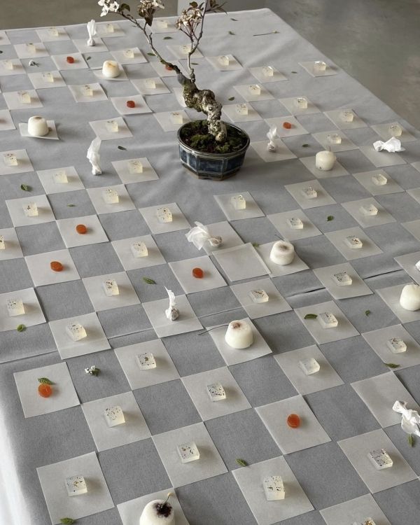 a checkered table cloth with small white flowers on it, and several pieces of paper scattered around the table