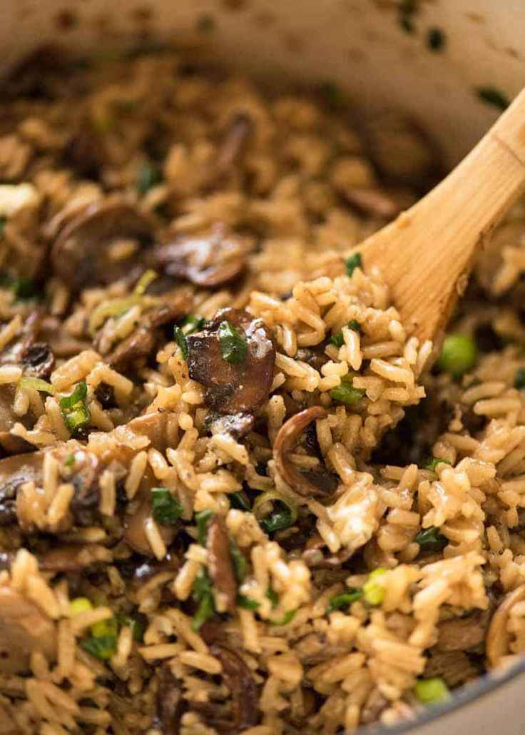 mushrooms and rice in a pot with a wooden spoon