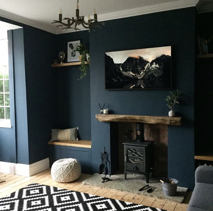 a living room with blue walls and a fireplace in the center, decorated with black and white rugs