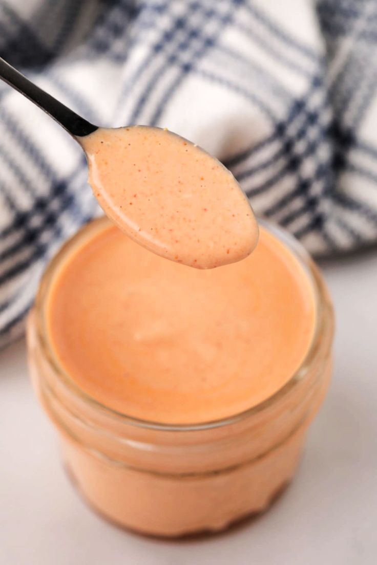 a spoon full of peanut butter on top of a jar