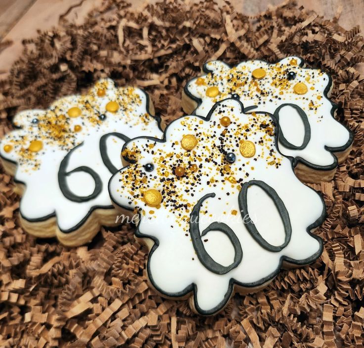 two decorated cookies sitting on top of a pile of brown and white paper machs