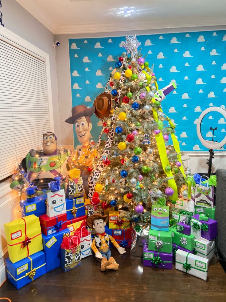 a christmas tree with toy story characters around it and presents on the floor next to it