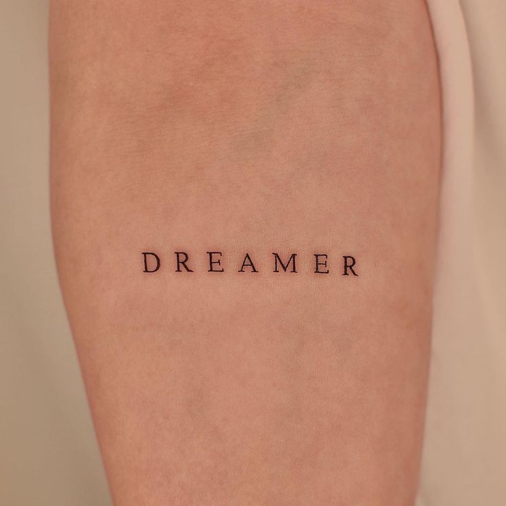 a woman's arm with the word dream written on it, in cursive font