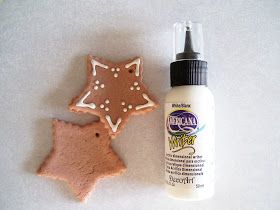 a bottle of glue next to a cookie shaped like a star and a gingerbread