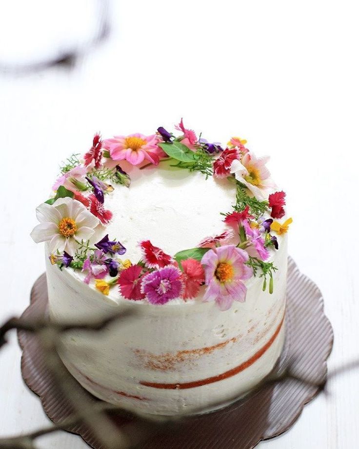 a white cake with flowers on it sitting on a plate next to a wire rack