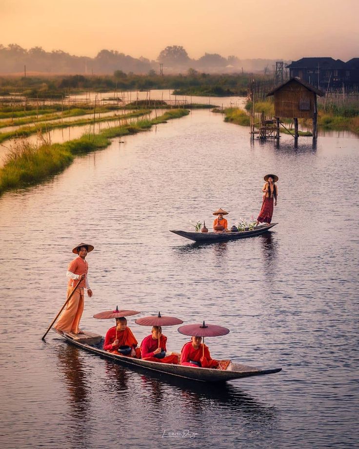 three people in boats paddling down a river at sunset or dawn with paddles