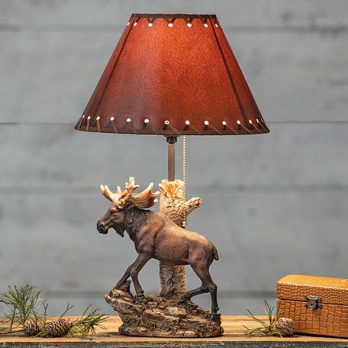 the moose lamp is next to an old suitcase and a christmas tree ornament