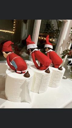 three elfs are sitting on toilet paper rolls