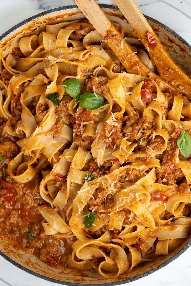 a skillet filled with pasta, meat and sauce on top of a marble counter